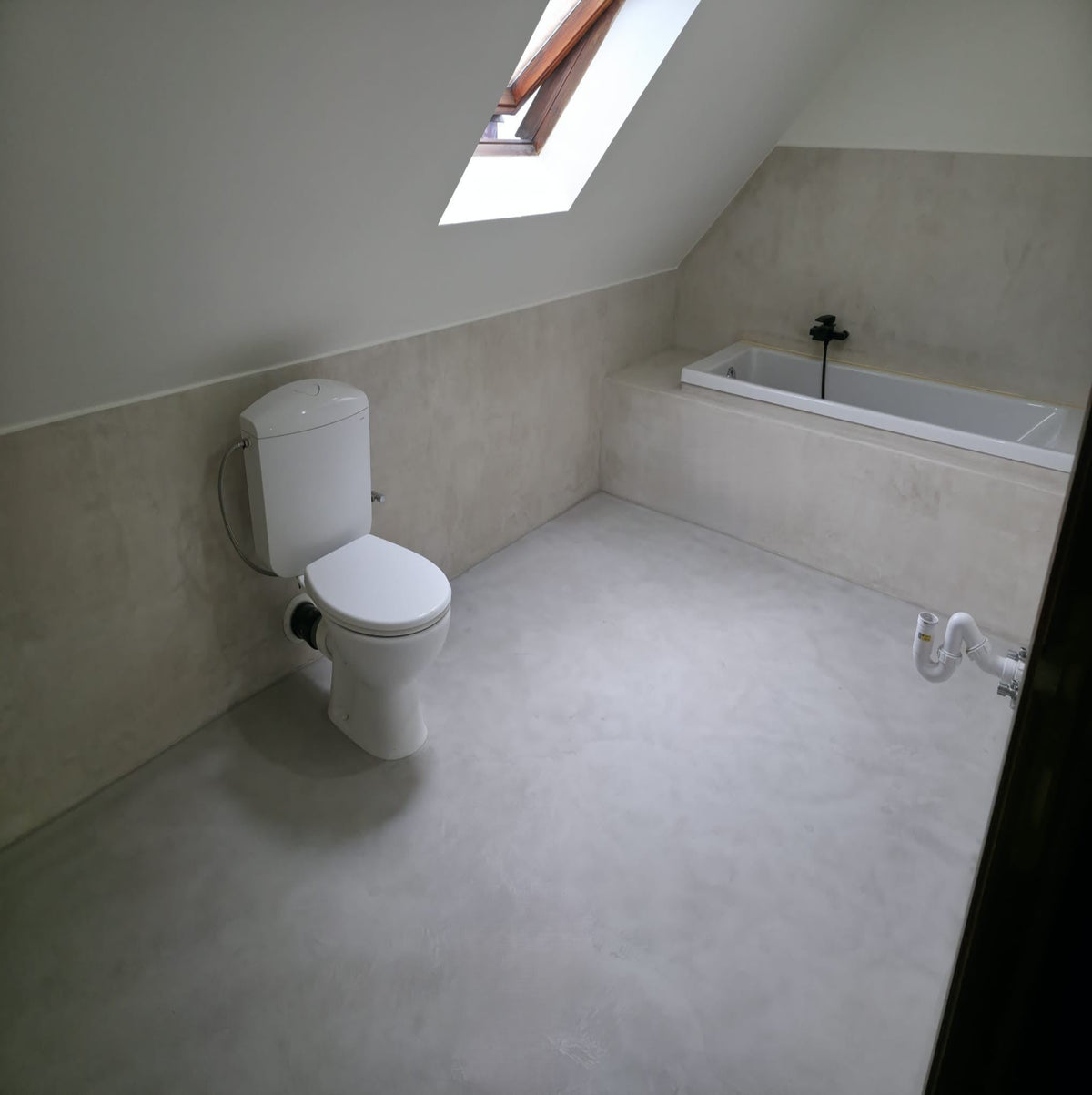 Bathroom with a toilet and bathtub under a skylight
