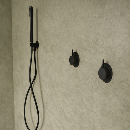 Black shower head and control handles mounted on a beige tiled Lime plaster on the tile wall.
