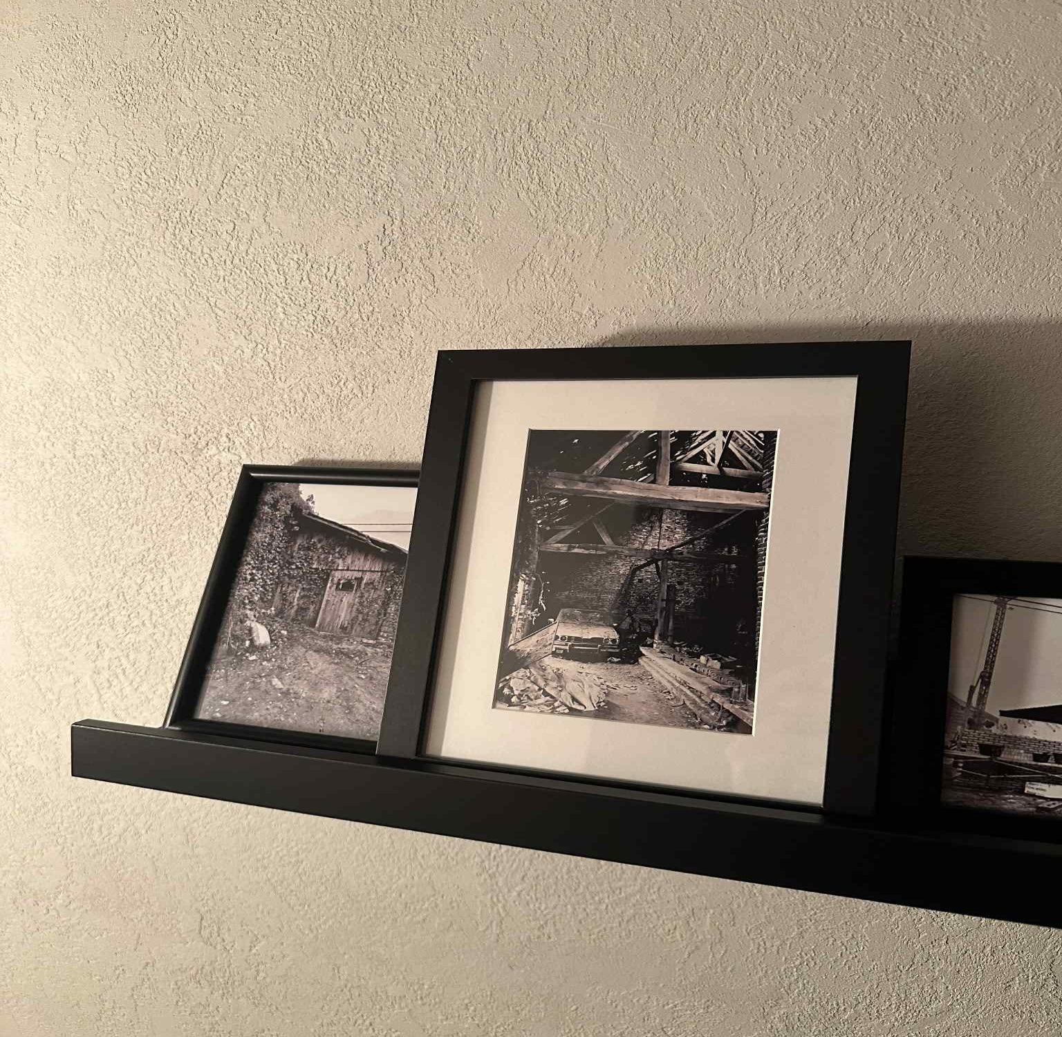 Three framed black and white photos on a textured wall