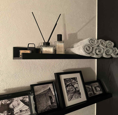 Shelf with diffuser, bottles, and towels against a neutral wall.
