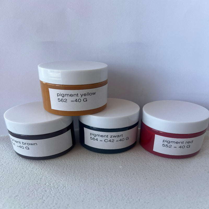 Four jars of different colored pigments stacked on a white surface with labels.