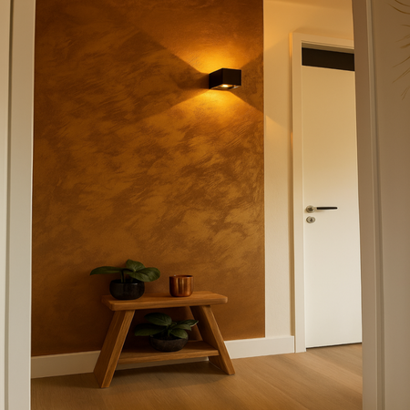Narrow hallway with a textured brown wall, wooden stool with plants, and a white door.