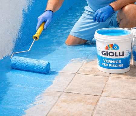 Man applying blue paint to a pool using a roller, wearing a Giolfi branded shirt.