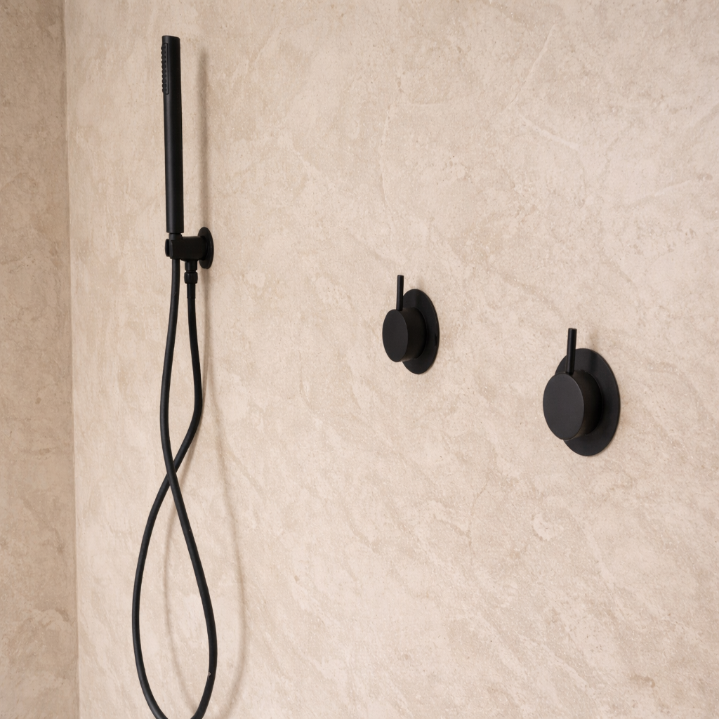Black shower head and control handles mounted on a beige textured wall.